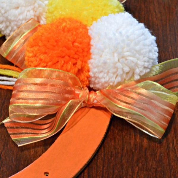 Bright, fluffy and Halloween-happy, Candy Corn Pompom Wreaths are candy-inspired holiday decor for doors or windows! At littlemisscelebration.com #crafts #halloween