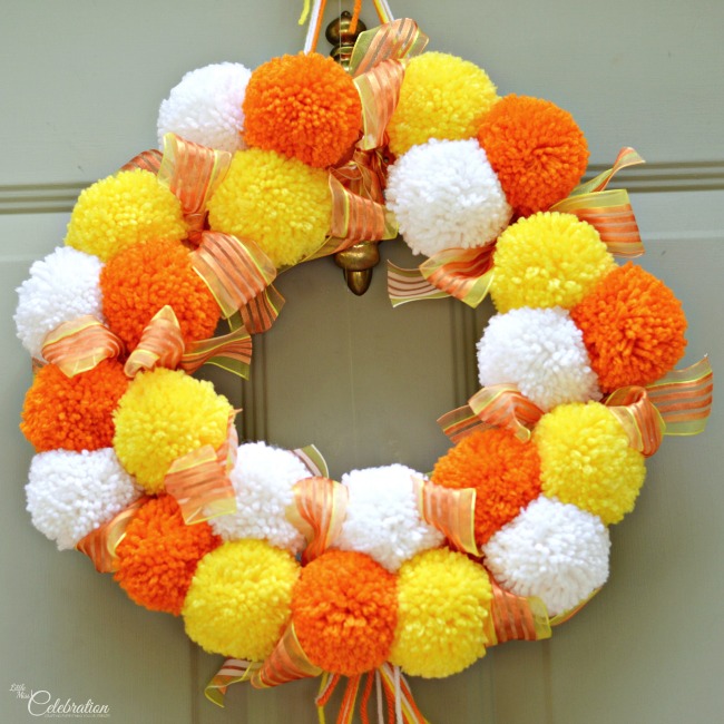 Bright, fluffy and Halloween-happy, Candy Corn Pompom Wreaths are candy-inspired holiday decor for doors or windows! At littlemisscelebration.com #crafts #halloween