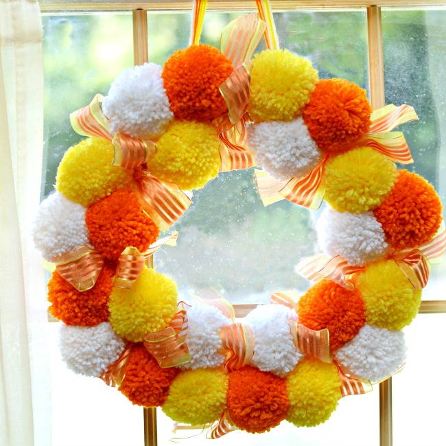 Bright, fluffy and Halloween-happy, Candy Corn Pompom Wreaths are candy-inspired holiday decor for doors or windows! At littlemisscelebration.com #crafts #halloween