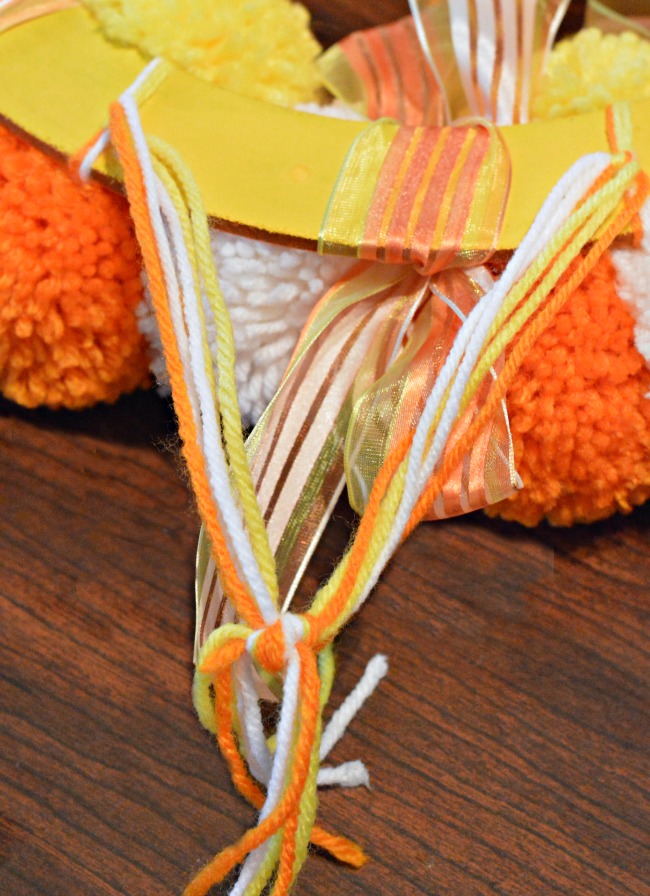 Bright, fluffy and Halloween-happy, Candy Corn Pompom Wreaths are candy-inspired holiday decor for doors or windows! At littlemisscelebration.com #crafts #halloween